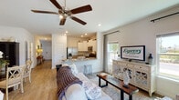 This two-story home in Callaway, Florida features three bedrooms and two and a half bathrooms, delivering a well-designed layout that balances open communal spaces with private retreats. The entry foyer welcomes you with warm hardwood-style flooring that flows throughout the main level, with a staircase leading to the upper floor. The open-concept living and dining area is bright and airy, enhanced by recessed lighting and a ceiling fan overhead. The adjacent kitchen is a standout feature, outfitted with crisp white shaker cabinets, granite countertops, stainless steel appliances including a French door refrigerator, microwave, electric range, and dishwasher, and a peninsula with bar seating that connects seamlessly to the living space. Natural light filters in through multiple windows. The dining area offers a cozy nook ideal for everyday meals. Upstairs, the primary bedroom is generously sized with large windows, a ceiling fan, and hardwood-style flooring. Additional bedrooms are well-proportioned with ample natural light and closet space. The bathrooms are clean and functional, including a full bath with a walk-in shower and built-in shelving. A convenient half bath is also included. The home's neutral color palette and consistent finishes throughout create a cohesive and move-in-ready aesthetic.