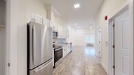Located at 44 Cortlandt in New Brunswick, NJ, this studio unit offers a thoughtfully designed open-concept layout that maximizes every square foot. Light wood-tone flooring runs throughout the space, complementing the bright, neutral walls and creating a clean, contemporary aesthetic.

The kitchen anchors one end of the unit and is well-appointed with white shaker cabinetry, granite-look countertops, a geometric tile backsplash, and a full suite of stainless steel appliances including a refrigerator, electric range, over-the-range microwave, and dishwasher. The kitchen flows seamlessly into the open living area, which benefits from recessed lighting and a window with outdoor views, allowing natural light to fill the space.

The bathroom features a walk-in shower with large-format marble-style tile surround and a white shower base, finished with chrome fixtures for a polished look. A dedicated laundry area houses a stacked washer and dryer unit, adding everyday convenience. A closet with built-in shelving provides organized storage. The overall ambiance is modern, bright, and functional, making efficient use of the open floor plan throughout.