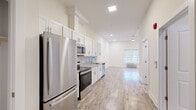 Located at 44 Cortlandt in New Brunswick, NJ, this studio unit offers a thoughtfully designed open-concept layout that maximizes every square foot. Light wood-tone flooring runs throughout the space, complementing the bright, neutral walls and creating a clean, contemporary aesthetic.

The kitchen anchors one end of the unit and is well-appointed with white shaker cabinetry, granite-look countertops, a geometric tile backsplash, and a full suite of stainless steel appliances including a refrigerator, electric range, over-the-range microwave, and dishwasher. The kitchen flows seamlessly into the open living area, which benefits from recessed lighting and a window with outdoor views, allowing natural light to fill the space.

The bathroom features a walk-in shower with large-format marble-style tile surround and a white shower base, finished with chrome fixtures for a polished look. A dedicated laundry area houses a stacked washer and dryer unit, adding everyday convenience. A closet with built-in shelving provides organized storage. The overall ambiance is modern, bright, and functional, making efficient use of the open floor plan throughout.