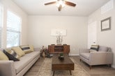 This single-floor residence offers a thoughtfully designed layout with a cohesive neutral color palette and wood-look flooring throughout the main living areas. The galley-style kitchen is outfitted with dark espresso cabinetry, stainless steel appliances, and light stone countertops, providing ample storage and workspace. Adjacent to the kitchen, the dining area features pendant lighting and light hardwood-style flooring, creating an inviting space for meals and gatherings. The living room is bright and airy, with multiple windows allowing natural light to fill the space. A ceiling fan adds comfort, and the mid-century modern furnishings complement the warm, neutral tones of the room. The bedroom is carpeted for added comfort and includes a ceiling fan, a window for natural light, and generous space for bedroom furniture. The full bathroom features dark wood vanity cabinetry, a single-sink vanity with a large mirror, and a shower-tub combination. A dedicated in-unit laundry room accommodates a full-sized washer and dryer side by side, complemented by overhead wire shelving for additional storage. Light vinyl plank flooring in the laundry area adds practicality. Overall, the residence delivers a functional and comfortable living environment with consistent finishes throughout.
