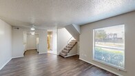 Located at 4721 W Walnut St in Garland, TX, this two-story home offers 2 bedrooms and 4 bathrooms thoughtfully arranged across two floors. The main level features an open-concept living, dining, and kitchen area with dark hardwood-style flooring, neutral-toned walls, and a textured ceiling. Ceiling fans provide comfort in the living areas, while large windows with blinds bring in natural light and outdoor views. A carpeted staircase connects the two floors, adding a practical transition between living spaces. The galley-style kitchen is equipped with white cabinetry, light stone countertops, and ample storage, including access to a dedicated pantry. The upper floor houses the bedrooms, each featuring plush carpeting, ceiling fans, and windows for natural light. The primary bedroom includes multiple closets and direct access to an en-suite bathroom. The bathrooms are well-appointed, with one featuring a tiled tub-and-shower combination with elegant stone-look tile accents and chrome fixtures. Additional highlights include five closets for generous storage, a utility room, and a hallway connecting the upper-level spaces. The home's practical layout and functional design make it a comfortable and well-organized residence.
