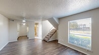 Located at 4721 W Walnut St in Garland, TX, this two-story home offers 2 bedrooms and 4 bathrooms thoughtfully arranged across two floors. The main level features an open-concept living, dining, and kitchen area with dark hardwood-style flooring, neutral-toned walls, and a textured ceiling. Ceiling fans provide comfort in the living areas, while large windows with blinds bring in natural light and outdoor views. A carpeted staircase connects the two floors, adding a practical transition between living spaces. The galley-style kitchen is equipped with white cabinetry, light stone countertops, and ample storage, including access to a dedicated pantry. The upper floor houses the bedrooms, each featuring plush carpeting, ceiling fans, and windows for natural light. The primary bedroom includes multiple closets and direct access to an en-suite bathroom. The bathrooms are well-appointed, with one featuring a tiled tub-and-shower combination with elegant stone-look tile accents and chrome fixtures. Additional highlights include five closets for generous storage, a utility room, and a hallway connecting the upper-level spaces. The home's practical layout and functional design make it a comfortable and well-organized residence.