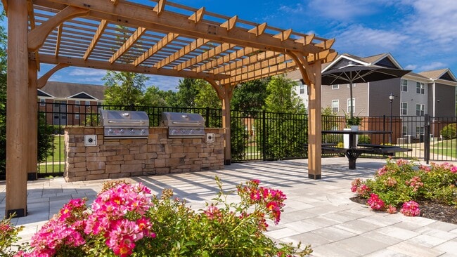 Enjoy beautifully landscaped walkways with wooden pergola shade and colorful flowering plants, professionally operated by Highlands Vista Group - The Foundry
