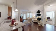 This single-floor residence offers a thoughtfully designed open-concept layout that seamlessly connects the kitchen, dining, and living areas. The kitchen is a standout feature, boasting rich wood cabinetry, granite countertops, stainless steel appliances, and a breakfast bar with pendant lighting — ideal for both everyday meals and casual entertaining. The living room is bright and welcoming, with a ceiling fan, hardwood-style flooring, and a glass door that fills the space with natural light. A dedicated dining area accommodates a full-sized table and is illuminated by a single pendant light, with a convenient door leading to the in-unit laundry area. The primary bedroom is a comfortable retreat, featuring plush carpeting, a ceiling fan, multiple windows, and ample natural light. A walk-in closet provides generous storage. The second bedroom offers a cozy atmosphere with soft carpet and tasteful wall space. The bathroom is well-finished with dark granite countertops, wood cabinetry, a tiled tub-shower combination, and hardwood-style flooring. Throughout the residence, neutral tones, consistent finishes, and thoughtful details create a cohesive and inviting atmosphere.