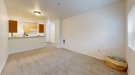 Located at 5800 NE Center Commons Way in Portland, Oregon, this one-bedroom, one-bathroom residence offers a well-organized single-floor layout designed to maximize functionality. The living room is carpeted and bathed in natural light courtesy of a full sliding glass door that opens to an outdoor view of surrounding greenery, creating a bright and welcoming atmosphere. The galley-style kitchen is efficiently arranged with warm wood-toned cabinetry lining both walls, a white appliance suite including a range and refrigerator, a dishwasher, a sink, and light wood-look flooring that provides easy maintenance underfoot. A hallway connects the main living area to the private quarters, passing by a full bathroom finished with wood-toned vanity cabinetry, a wide mirror, a shower/tub combination, and wood-look flooring. The bedroom offers a cozy carpeted retreat with a window that draws in natural light and convenient access to a dedicated closet. A second closet provides additional storage within the unit. Throughout, clean white walls and neutral tones create a consistent, move-in-ready aesthetic that is both practical and comfortable.