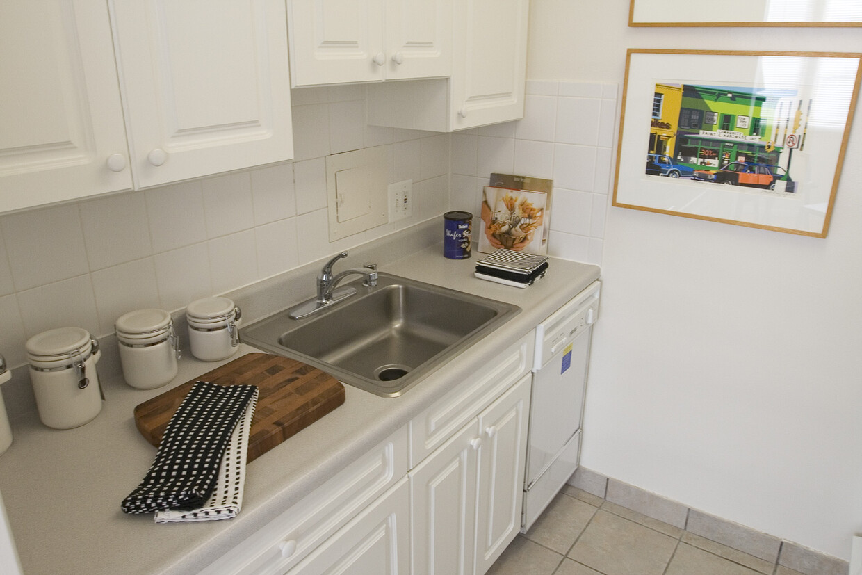 Studio apartment kitchen with large stainless steel sink, dishwasher and white cabinets - The Statesman