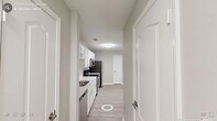 Located at 1400 E Cornwallis Rd in Durham, NC, this single-floor, 2-bedroom, 1-bathroom residence offers a clean, modern design with a neutral color palette throughout. The kitchen is a functional highlight, featuring white cabinetry, light quartz-style countertops, and a full suite of stainless steel appliances including a refrigerator, electric range, microwave, and dishwasher. Light wood-style flooring runs through the main living areas, complementing the bright, airy atmosphere. The open layout connects the kitchen seamlessly to the living area, which benefits from large windows offering views of surrounding greenery. Both bedrooms are generously sized, with soft carpeting, ceiling fans with integrated lighting, and windows that invite natural light and tree-lined views. The spacious primary bedroom provides ample room for a full furniture arrangement. The shared bathroom is well-appointed with a white vanity, under-sink storage, a large mirror, and a lighted fixture above. A dedicated closet provides additional storage. Textured ceilings and clean white trim are consistent throughout, giving the space a polished, well-maintained feel. The overall ambiance is bright, neutral, and move-in ready.