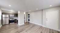 This thoughtfully renovated single-floor residence combines clean, modern finishes with a practical and comfortable layout. Throughout the main living areas, durable wood-look luxury vinyl plank flooring flows seamlessly beneath recessed lighting, all set against a neutral gray-and-white color palette that creates a bright, airy atmosphere. Large windows dressed with white blinds bring in generous natural light across every room.

The open-concept living area connects directly to a well-equipped kitchen featuring dark, rich cabinetry, a subway tile backsplash, white countertops, and a full suite of stainless steel appliances including a gas range, microwave, refrigerator, and sink. A dedicated in-unit stacked washer and dryer adds everyday convenience.

The bedrooms offer a softer, cozier feel with plush wall-to-wall carpeting, ceiling fans, window-mounted air conditioning units, and ample closet space. Natural light filters in through blinded windows, maintaining a calm and restful atmosphere.

The bathroom is a standout feature, finished with a striking floor-to-ceiling marbled tile surround in cool blue and gray tones complementing a soaking tub and clean white vanity. Throughout the space, crisp white trim, solid doors, and consistent finishes reflect a careful attention to detail in the renovation.