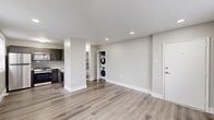 This thoughtfully renovated single-floor residence combines clean, modern finishes with a practical and comfortable layout. Throughout the main living areas, durable wood-look luxury vinyl plank flooring flows seamlessly beneath recessed lighting, all set against a neutral gray-and-white color palette that creates a bright, airy atmosphere. Large windows dressed with white blinds bring in generous natural light across every room.

The open-concept living area connects directly to a well-equipped kitchen featuring dark, rich cabinetry, a subway tile backsplash, white countertops, and a full suite of stainless steel appliances including a gas range, microwave, refrigerator, and sink. A dedicated in-unit stacked washer and dryer adds everyday convenience.

The bedrooms offer a softer, cozier feel with plush wall-to-wall carpeting, ceiling fans, window-mounted air conditioning units, and ample closet space. Natural light filters in through blinded windows, maintaining a calm and restful atmosphere.

The bathroom is a standout feature, finished with a striking floor-to-ceiling marbled tile surround in cool blue and gray tones complementing a soaking tub and clean white vanity. Throughout the space, crisp white trim, solid doors, and consistent finishes reflect a careful attention to detail in the renovation.