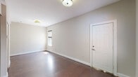 Located at 627 W Lexington St in Baltimore, Maryland, this single-floor unit offers a well-organized layout with a clean, modern aesthetic. The main living area is open and bright, showcasing rich dark hardwood floors that run throughout the space. Neutral gray-toned walls and crisp white trim and baseboards create a fresh, cohesive look, while flush-mount light fixtures provide consistent overhead lighting. A window allows natural light to filter in, complementing the airy feel of the room.

The kitchen is a standout feature, equipped with rich dark wood cabinetry, granite countertops, and a metallic penny-tile backsplash that adds texture and visual interest. Stainless steel appliances, including a refrigerator, dishwasher, and range, complete the functional and stylish kitchen. A corner sink with a modern faucet is thoughtfully integrated into the countertop layout.

The bathroom is finished with large-format travertine-style tile flooring, a dark wood vanity with a light-toned countertop and undermount sink, and a frameless mirror above. The overall design is consistent and practical. The unit's compact, efficient floor plan makes excellent use of available space throughout.