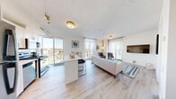 This well-designed 2-bedroom, 2-bathroom unit offers a modern, open-concept layout bathed in natural light from expansive floor-to-ceiling windows. Light hardwood flooring runs throughout the space, complementing the clean, neutral color palette and contemporary finishes.

The kitchen is appointed with white shaker cabinetry, a white quartz peninsula with bar seating, a white subway tile backsplash, and stainless steel appliances — all framed by a large window offering sweeping urban views. The kitchen flows seamlessly into a dedicated dining area, which features a glass dining table and a large framed mirror that amplifies the sense of space. The open living room is bright and airy, with two floor-to-ceiling windows and direct views of the surrounding cityscape.

Both bedrooms are compact yet well-proportioned, each featuring floor-to-ceiling windows that bring in generous natural light and urban views. The two bathrooms are finished consistently with white cabinetry, single vanities, tiled tub-shower combinations, and neutral tile flooring. Two hallways provide practical circulation and access throughout the unit, with in-unit laundry connections also present. The overall ambiance is modern, clean, and light-filled — making efficient use of every square foot.