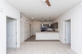 This single-floor residence in East Point, Georgia, is designed with a clean, modern aesthetic and a functional open-concept layout. The kitchen serves as a central feature, showcasing rich dark-brown cabinetry paired with light countertops, a geometric tile backsplash, and a full suite of black appliances including a refrigerator, range, over-the-range microwave, and dishwasher. Wood-look plank flooring runs throughout the kitchen and main living areas, while pendant lighting above the kitchen peninsula adds a contemporary touch. The peninsula itself provides both additional prep space and a natural transition into the living area, which is finished with plush carpet and benefits from natural light through large windows fitted with blinds.

The bedrooms are generously sized, each carpeted and equipped with ample natural light from oversized windows. Storage is well-addressed, with multiple walk-in closets outfitted with wire shelving systems along multiple walls. The bathrooms feature the same dark cabinetry as the kitchen, light countertops, wood-look flooring, and a standalone walk-in shower in the primary bath. The overall palette of neutral tones and consistent finishes gives the space a cohesive, move-in-ready feel.