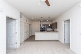 This single-floor residence in East Point, Georgia, is designed with a clean, modern aesthetic and a functional open-concept layout. The kitchen serves as a central feature, showcasing rich dark-brown cabinetry paired with light countertops, a geometric tile backsplash, and a full suite of black appliances including a refrigerator, range, over-the-range microwave, and dishwasher. Wood-look plank flooring runs throughout the kitchen and main living areas, while pendant lighting above the kitchen peninsula adds a contemporary touch. The peninsula itself provides both additional prep space and a natural transition into the living area, which is finished with plush carpet and benefits from natural light through large windows fitted with blinds.

The bedrooms are generously sized, each carpeted and equipped with ample natural light from oversized windows. Storage is well-addressed, with multiple walk-in closets outfitted with wire shelving systems along multiple walls. The bathrooms feature the same dark cabinetry as the kitchen, light countertops, wood-look flooring, and a standalone walk-in shower in the primary bath. The overall palette of neutral tones and consistent finishes gives the space a cohesive, move-in-ready feel.