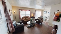 Located at 8930 Longbranch Trail in Fort Worth, Texas, this two-story home offers a practical and comfortable layout across both levels. The main living area is spacious and inviting, featuring warm hardwood-style flooring, multiple windows dressed with decorative curtains that allow generous natural light, and a textured ceiling that adds character throughout. Seating flows naturally into an adjacent dining area, creating an open and connected feel on the main floor. The kitchen is well-equipped with warm wood cabinetry, ample counter space, a double basin sink, and built-in appliances, including a dishwasher and refrigerator. A staircase with a tall vertical window brings additional natural light into the transition between floors. Upstairs, the bedrooms are carpeted and comfortably sized, each featuring closet storage and windows for natural light. One bedroom includes a built-in desk area, offering versatility as a study or secondary sleeping space. The bathrooms feature wood-toned vanity cabinetry, well-lit mirrors, and a tiled tub and shower combination. Throughout the home, the textured ceilings and neutral wall tones create a cohesive, understated aesthetic suited to a variety of living arrangements.
