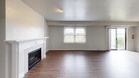 Located at 985 N Broadway in De Pere, Wisconsin, this well-appointed two-bedroom, two-bathroom single-floor home offers a thoughtfully designed layout with a clean, neutral aesthetic throughout. The spacious living room serves as the heart of the home, anchored by a classic white-mantled fireplace and wood-look flooring that extends across the main living areas. A large window frames pleasant outdoor views, filling the room with natural light and a welcoming ambiance. The living area flows seamlessly into a dedicated dining or flex space, which connects directly to the kitchen. The kitchen is equipped with stainless steel appliances, including a full-size refrigerator, and features a practical countertop with built-in seating. Both bedrooms are generously sized, with the primary bedroom offering ample space, plush carpeting, a closet, and direct access to a private en-suite bathroom. The second bedroom also features carpeting, a built-in closet, and a window with outdoor views. The primary bathroom is finished with white cabinetry, a quartz-style countertop, a large mirror with pendant lighting, and white tile wainscoting, while the second bathroom includes a full tub/shower combination. A hallway connects the rooms efficiently, and a dedicated closet provides additional storage.