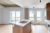 This 43 square meter apartment in Montréal offers a harmonious blend of modern design and functionality. The space comprises one bedroom, one bathroom, and an open-concept kitchen, all distributed across a single floor. The primary bedroom, measuring 11 square meters, provides a cozy retreat.

The apartment's design embraces an industrial-inspired aesthetic, evident in the exposed concrete ceilings that add character and height to the rooms. This raw element is beautifully contrasted with sleek, white walls and warm wooden flooring throughout, creating a balanced and inviting atmosphere.

The kitchen is a standout feature, boasting a contemporary design with a mix of light and dark wood cabinetry. Stainless steel appliances, including a built-in oven and cooktop, complement the modern look. A unique backsplash with a subtle wave pattern adds visual interest, while the pendant lighting enhances the overall ambiance.

The bathroom continues the modern theme with a floating wooden vanity, large mirror, and clean lines. The bedroom, while compact, offers ample storage with built-in closets featuring sliding doors. Large windows in both the bedroom and kitchen allow natural light to flood the space, creating a bright and airy feel.

This apartment efficiently utilizes its 43 square meters, offering a stylish and comfortable living space in the heart of Montréal.