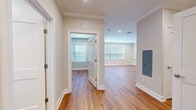 Located at 15 Station Rd in Brookfield, CT, this single-floor, two-bedroom, one-bathroom residence offers a thoughtfully designed layout with consistent, modern finishes throughout. Warm hardwood-style flooring runs continuously across every room, complemented by crisp white crown molding and clean baseboards that lend the space a polished, cohesive look.

The open kitchen and living area serves as the heart of the unit. The kitchen features a striking navy blue island with dark granite countertops, an integrated sink, and recessed lighting overhead. Stainless steel appliances, including a full-size refrigerator, complete the functional setup. White upper cabinetry adds contrast and storage. The adjacent living area flows naturally from the kitchen, benefiting from recessed lighting and a glazed entry door that introduces natural light.

The primary bedroom offers a comfortable footprint with a closet and neutral-toned walls. The second bedroom is similarly finished, providing flexibility for various uses. Both rooms share access to the bathroom, which includes a full tub-shower combination with white subway tile surround and chrome fixtures.

A dedicated laundry area is accessible from the bedroom corridor, adding everyday convenience. The unit also features a visible electrical panel and HVAC vents, underscoring its practical, move-in-ready condition throughout.