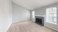 Located in Lakewood, WA, this single-floor unit offers four bedrooms, one bathroom, a combined kitchen and living room, and a hallway connecting the main spaces. The living room is a standout area, featuring a tile-surround fireplace, a ceiling fan, soft carpet underfoot, and a sliding glass door that invites natural light and outdoor views. A hallway leads from the living area through to the bedrooms, each finished with plush carpet, soft gray walls, and individual windows that allow for ample daylight. The primary bedroom includes a closet and direct access to the shared hallway. Additional bedrooms are well-proportioned, each with baseboard heating and natural light from well-placed windows. The bathroom is clean and functional, equipped with a full tub-shower combination and chrome fixtures. The kitchen features gray shaker-style cabinetry, light countertops, a stainless steel sink, and black appliances including a refrigerator and electric range, all set over warm wood-look flooring. A dedicated laundry area with a washer and dryer is conveniently accessible from the living space. The overall aesthetic throughout is neutral and cohesive, with consistent gray-toned walls and white trim creating a clean, move-in-ready environment.