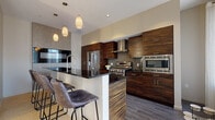 Located on Euclid Avenue in the heart of Cleveland, this contemporary urban residence delivers a sophisticated living experience with thoughtfully curated finishes throughout. The open-concept kitchen is a standout centerpiece, showcasing bold zebra-wood cabinetry, dark granite countertops, a breakfast bar with stylish upholstered stools, stainless steel appliances, and pendant lighting. A textured mosaic accent wall and tile backsplash add visual depth to the culinary space.

The living room is bright and welcoming, with large picture windows framing dynamic views of Cleveland's downtown skyline. Light hardwood flooring flows through the main living areas, complementing the neutral, warm-toned palette. A sleek built-in entertainment wall adds a modern, polished touch.

The bedroom offers a serene retreat with patterned carpeting, a textured accent wall, and a stacked in-unit washer and dryer conveniently accessible nearby. The bathroom is elegantly appointed with large-format tile walls, a floating wood vanity with vessel sink, an illuminated mirror, and slate-toned floor tile. Every detail reflects a commitment to modern design, making this residence a refined and functional urban home in the heart of Cleveland.