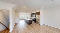 Located at 91 Summit Dr in Barboursville, VA, this three-story townhouse offers a well-organized layout distributed across three distinct levels. The entry-level ground floor houses an attached garage with a paneled door featuring clerestory windows for natural light, along with an entrance that leads to the main living areas above.

The expansive main level serves as the social heart of the home, combining the living room, dining room, and kitchen in a single open-concept space. The kitchen is a standout feature, showcasing dark espresso cabinetry, stainless steel appliances, a subway tile backsplash, and a large central island with a white quartz countertop and pendant lighting above. Light hardwood-style flooring runs throughout, complementing the bright, recessed-lit ceiling. A sliding glass door in the living area opens to an outdoor balcony, filling the room with natural light.

The upper floor accommodates all three bedrooms, five bathrooms, two closets, and a laundry room. The primary bedroom offers a comfortable footprint with carpet flooring, a ceiling fan, and a spacious walk-in closet fitted with wire shelving. Bathrooms feature tile surrounds, soaking tubs, and clean white vanities. Additional bedrooms include ceiling fans, carpet, and large windows with exterior views, ensuring ample natural light throughout.