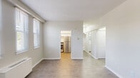 Located at 216 Fountain Street in New Haven, CT, this efficiently laid-out single-floor unit makes thoughtful use of its compact footprint. The living room serves as the central gathering space, featuring wood-look flooring, soft neutral walls, and a row of windows fitted with blinds that invite natural light while maintaining privacy. A wall-mounted heater ensures year-round comfort in this bright, open area.

The kitchen is well-appointed with warm wood-toned lower cabinetry, white upper cabinets extending to the ceiling for ample storage, light marble-style countertops, a stainless steel refrigerator, a stainless electric range, and a single-basin sink — all complemented by light vinyl flooring. An adjacent pantry provides additional storage convenience.

The bathroom is clean and functional, featuring white tile walls surrounding a full bathtub with shower, a toilet, a vanity with sink, and a large mirror with overhead lighting and light wood-style flooring.

The layout also includes a dedicated entrance, a connecting hallway, and two closets that add practical storage. Throughout the unit, consistent wood-look flooring, crisp white trim, and a neutral color palette create a cohesive, clean aesthetic that maximizes the sense of space.