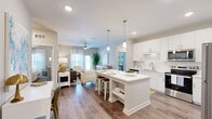 This well-appointed 2-bedroom, 2-bathroom residence at 300 Perigon Dr in Palm Coast, Florida offers a thoughtfully designed single-floor layout with a comfortable sense of space throughout. The open-concept kitchen is a standout feature, showcasing crisp white cabinetry, a subway tile backsplash, stainless steel appliances, and a generous quartz-topped island with built-in shelving — ideal for both meal prep and casual dining. Pendant lighting and wood-look flooring complete the polished look. The kitchen flows seamlessly into the living room, which is bathed in natural light from a glass door leading to the outdoors. A ceiling fan, neutral palette, and ample room for seating create a relaxed, inviting atmosphere. The primary bedroom is a serene retreat, carpeted for comfort, with ceiling fan and access to a long en-suite bathroom featuring a dual-sink vanity, walk-in shower, and a spacious walk-in closet with wire shelving. The second bedroom is equally comfortable, with natural light, a ceiling fan, and a nearby full bathroom with a tub-shower combo and quartz vanity. Additional conveniences include two closets, a utility room, and a hallway connecting all areas for a practical and efficient flow throughout the home.