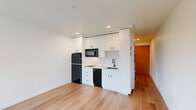 Located at 1341 N Killingsworth Street in Portland's Killingsworth corridor, this efficiently designed studio unit offers a thoughtful layout that maximizes every square foot of its compact footprint. The open main living area features light-toned hardwood flooring throughout, crisp white walls, and a large window that frames a neighborhood view and draws in natural light, creating a bright and airy atmosphere.

The kitchenette is well-appointed with white shaker-style cabinetry extending to the ceiling for ample storage, a subway tile backsplash, and a full suite of black appliances including a refrigerator, over-the-range microwave, dishwasher, and a single-basin sink — all contributing to a clean, contemporary aesthetic.

A dedicated alcove houses a stacked washer and dryer unit, providing the convenience of in-unit laundry. The full bathroom features a tub/shower combination with sleek matte black fixtures set against a pristine white surround, maintaining the modern, minimalist design language found throughout the space.

The unit's clean lines, neutral color palette, and modern finishes make it a functional and stylish option, well-suited for those seeking an efficient living space in North Portland.