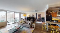 Located at 728 S Fourth St in downtown Louisville, Kentucky, this single-floor residence offers a lively and eclectic living experience defined by bold design choices and urban energy. The open living area features rich hardwood flooring, crown molding, and large floor-to-ceiling windows that flood the space with natural light and provide sweeping city views. A striking Louisville skyline wall mural serves as a dramatic focal point, complementing the vibrant, curated décor throughout. Sliding glass doors lead to a private balcony, extending the living space outdoors.

A secondary sitting room showcases a boldly patterned, colorful accent wall adorned with an eclectic gallery of mirrors and frames, adding personality and visual depth. Soft carpet underfoot and ample natural light from wide windows make this room an inviting retreat.

The kitchen is well-equipped, featuring warm cherry wood cabinetry, granite countertops, hardwood flooring, and black appliances including a range and built-in microwave. Generous cabinet storage and a functional layout make it practical for everyday use.

The bathrooms offer tiled tub-shower combinations, mosaic tile flooring, and playful painted ceilings in teal and yellow tones, lending each space a distinctive, artistic character. Throughout the residence, the design balances color, texture, and urban sophistication.