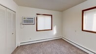 This single-floor residence features 3 bedrooms and 2 bathrooms within a well-organized, functional layout. The combined kitchen and living area serves as the heart of the home, with the kitchen outfitted with warm honey-toned wood cabinetry, ample upper and lower storage, a gas range, and a full-size refrigerator, all set on easy-care tile flooring. The living area flows naturally from the kitchen, featuring carpet flooring, baseboard heating, and a large picture window with wood trim that brings in natural light and outdoor views.

Each of the three bedrooms is carpeted and features wood-trimmed windows with blinds, baseboard heating, and louvered bi-fold closet doors providing practical storage. The primary bedroom includes a wall-mounted air conditioning unit for added comfort. A carpeted hallway connects the bedrooms, with additional closet storage accessible along the corridor.

The two bathrooms are cleanly appointed, with one featuring a full tub-shower combo surrounded by classic white square tile and chrome fixtures. Throughout the home, neutral white walls, textured ceilings, and warm wood-toned door and window trim create a consistent, understated aesthetic. Baseboard heating is present throughout, ensuring even warmth across the entire floor plan.