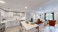 Located at 15120 Idlewild Road in Matthews, NC, this well-appointed single-floor residence offers 2 bedrooms, 2 bathrooms, an office, and a thoughtfully designed layout that maximizes both function and comfort. The open-concept kitchen is a standout feature, showcasing white shaker cabinetry, a subway tile backsplash, stainless steel appliances including a wall-mounted range hood, a stainless undermount sink with a matte black faucet, and a central island with quartz countertops and seating for two. Wood-look plank flooring flows throughout the main living areas, creating a warm, cohesive aesthetic. The living room is bright and welcoming, with recessed lighting, large windows dressed in navy drapes, and direct access to an exterior door. The primary bedroom is generously proportioned, featuring plush carpet, a ceiling fan with light, a tray ceiling detail, and a window that brings in natural light. A spacious walk-in closet with wrap-around shelving and rod systems provides ample storage. The bathrooms are finished with wide-format wood-look tile flooring, white cabinetry, quartz countertops, and matte black hardware. A dedicated office and additional closet round out the functional layout of this well-designed Matthews residence.