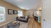 Located at 12 Wilkinson Way in Bluffton, South Carolina, this single-floor residence offers a thoughtfully designed layout with contemporary finishes and a warm, neutral color palette throughout. The living room provides a welcoming entry point, featuring wood-look plank flooring, large windows with natural light, and a comfortable, open feel suited for relaxing or entertaining.

The kitchen is a standout space, outfitted with rich dark cabinetry, granite countertops, under-cabinet lighting, and a full suite of stainless steel appliances including a range, built-in microwave, and refrigerator. A central island with a granite surface and integrated sink offers bar seating, making it ideal for casual dining or meal prep.

The bedrooms are generously sized, each featuring ceiling fans with light fixtures, wood-look flooring, and abundant natural light from multiple windows. Walk-in closet access is visible in at least one bedroom, adding practical storage. The soft, neutral wall tones create a calm and restful atmosphere.

The bathroom is finished with dark cabinetry, a granite vanity top, tile-surround tub and shower combination, and matching wood-look flooring, maintaining a consistent aesthetic with the rest of the residence. Overall, this home combines functional design with modern style in a cohesive and well-maintained package.