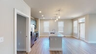 Located at 5701 Glenwood Ave in Raleigh, NC, this single-floor unit offers a thoughtfully designed open-concept layout that seamlessly connects the kitchen and living areas. The kitchen serves as a central hub, anchored by a granite-topped island with an integrated sink and pendant lighting overhead. Gray shaker-style cabinetry extends to the ceiling, complemented by a white tile backsplash, stainless steel appliances—including a refrigerator, range, and microwave—and a dedicated pantry closet. Light wood-style flooring flows throughout the main living areas, enhancing the bright, airy atmosphere created by multiple windows with blinds.

The living area is generously proportioned and open, allowing for flexible furniture arrangements. Bedrooms feature plush carpet flooring and closets with built-in shelving. The bathrooms are well-appointed; one includes a soaking tub with marble-style tile surround, while another features a glass-enclosed walk-in shower with matching tile, a granite-topped vanity with navy blue cabinetry, and wood-look flooring. Recessed lighting throughout the unit adds a clean, modern touch to the overall aesthetic.
