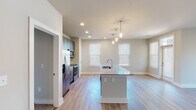 Located at 5701 Glenwood Ave in Raleigh, NC, this single-floor unit offers a thoughtfully designed open-concept layout that seamlessly connects the kitchen and living areas. The kitchen serves as a central hub, anchored by a granite-topped island with an integrated sink and pendant lighting overhead. Gray shaker-style cabinetry extends to the ceiling, complemented by a white tile backsplash, stainless steel appliances—including a refrigerator, range, and microwave—and a dedicated pantry closet. Light wood-style flooring flows throughout the main living areas, enhancing the bright, airy atmosphere created by multiple windows with blinds.

The living area is generously proportioned and open, allowing for flexible furniture arrangements. Bedrooms feature plush carpet flooring and closets with built-in shelving. The bathrooms are well-appointed; one includes a soaking tub with marble-style tile surround, while another features a glass-enclosed walk-in shower with matching tile, a granite-topped vanity with navy blue cabinetry, and wood-look flooring. Recessed lighting throughout the unit adds a clean, modern touch to the overall aesthetic.