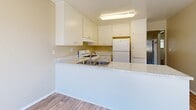 Located at 3935 La Sierra Ave in Riverside, California, this single-floor, 2-bedroom, 1-bathroom unit offers a practical and comfortable layout with a neutral color palette throughout. The kitchen is a functional highlight, featuring white cabinetry, light stone-look countertops, a peninsula with a stainless steel sink, and white appliances including a gas range, dishwasher, and refrigerator. Wood-look flooring runs through the kitchen and connects seamlessly to the dining and living areas, creating a cohesive flow. The living room is generously proportioned, featuring a textured ceiling, a wall-mounted A/C unit, and a large window with vertical blinds that invites natural light. Both bedrooms are carpeted and offer a calm, neutral ambiance. The primary bedroom includes a ceiling fan with light fixture, a sizable window for natural light, and access to closet space. The secondary bedroom also features carpeting, a textured ceiling, and a wall vent. Three closets throughout the unit provide ample storage. The bathroom is finished with wood-look tile flooring, a granite-style vanity countertop, and a full-size soaking tub with shower. A connecting hallway ties the layout together efficiently, making this unit a well-organized and livable space.