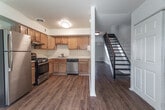 Located at 2004 Seldendale Dr in Hampton, Virginia, this two-story home offers a practical and comfortable layout across two levels. The main floor features rich hardwood-style flooring that flows through the open living area, which is brightened by a sliding glass door that invites natural light and provides outdoor access. A staircase with classic wrought iron railings connects the two floors, adding a traditional architectural touch as seen in the dollhouse overview. The kitchen is well-equipped with warm oak cabinetry, white countertops, a gas range, a stainless steel dishwasher, and a double sink — all set atop matching hardwood-style flooring. A bathroom on this level includes a full tub-shower combination, wood vanity cabinetry, and coordinating hardwood flooring. Upstairs, the bedrooms are carpeted for comfort and feature neutral walls, large windows that bring in ample natural light, and individual closets with built-in shelving for storage. Each bedroom offers a quiet, functional retreat with views of the surrounding neighborhood. Throughout the home, the design is clean and straightforward, with white walls and simple finishes that create a bright, move-in-ready atmosphere suited to a variety of lifestyles.
