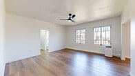 Located at 1775 N Orange Dr in the heart of Hollywood, Los Angeles, this thoughtfully designed single-floor unit offers a clean, modern aesthetic throughout. The open living room serves as the centerpiece of the space, featuring warm wood-look flooring, crisp white walls, and a sleek black ceiling fan with integrated lighting. A bank of multi-pane windows floods the room with abundant natural light and provides views of the surrounding neighborhood, creating an airy and inviting atmosphere. A charming arched doorway adds a subtle architectural detail, connecting the living area to the hallway beyond.

The galley-style kitchen is efficiently laid out, with white cabinetry, dark countertops, and stainless steel appliances including a gas range and refrigerator. Matching wood-look flooring runs continuously throughout, maintaining a cohesive design.

The bathroom is finished in a crisp white palette, featuring subway tile walls with bold black accents, a pedestal sink with a matte black faucet, a combination tub and shower, and a gridded window that brings in natural light. A dedicated closet provides practical storage. The hallway connects each area smoothly, contributing to the unit's efficient and well-organized single-level layout.