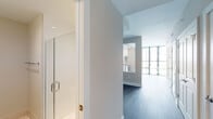 Located at 33 Monroe St in Rockville, Maryland, this single-floor residence offers a thoughtfully designed layout with modern finishes throughout. Dark hardwood-style flooring flows seamlessly across the open living and dining areas, creating a cohesive and sophisticated aesthetic. The living space is bright and airy, benefiting from expansive floor-to-ceiling windows dressed with horizontal blinds that allow for controlled natural light and views of the surrounding urban landscape.

The kitchen is a standout feature, outfitted with a clean combination of white upper cabinetry and warm wood-toned lower cabinets, complemented by a classic white subway tile backsplash. Stainless steel appliances — including a gas range, built-in microwave, dishwasher, and refrigerator — are paired with a sleek countertop and undermount sink. Track lighting overhead adds both functionality and a contemporary touch.

A pass-through window connects the kitchen to the living area, enhancing the open feel of the space. The bathroom is finished with large-format light tile flooring, a wood-toned vanity with a stone countertop, and a glass-enclosed shower, all contributing to a clean and refined atmosphere.

Neutral wall tones throughout the residence provide a versatile backdrop, making this a well-balanced and move-in-ready urban home.