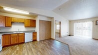 Located at 5001 Amber Valley Pkwy S in Fargo, North Dakota, this single-floor residence offers 2 bedrooms and 3 bathrooms with a practical, well-organized layout. The kitchen is a functional highlight, featuring warm oak cabinetry with ample upper and lower storage, granite-style countertops, and white appliances including a refrigerator, range, microwave, and dishwasher. Durable hardwood-style flooring runs throughout the kitchen and connecting areas, transitioning to plush carpet in the living and bedroom spaces. The living room is spacious and bright, with a sliding glass door fitted with vertical blinds that allows natural light and exterior access. Baseboard heating is present throughout, ensuring comfort during colder months, and a wall-mounted air conditioning unit serves the living area. The primary bedroom is generously sized and includes a walk-in closet with built-in shelving and rack storage, as well as a private en-suite bathroom with a full tub/shower, oak vanity, and hardwood-style flooring. The second bedroom is well-proportioned with a window offering outdoor views and its own closet. Three bathrooms in total provide excellent convenience for residents and guests. A hallway connects the main living spaces efficiently, and a textured ceiling finish is consistent throughout the home.