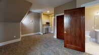 Located at 888 Delaware Ave in Buffalo, NY, this one-bedroom, one-bathroom residence offers a compact yet characterful living experience defined by its unique upper-floor architecture. The space showcases the charm of a classic roofline interior, with angled ceilings and dormer-style wall cutouts that add architectural interest throughout. Neutral taupe walls and crisp white trim create a warm, cohesive palette, while plush wall-to-wall carpeting runs through the main living areas, hallway, and bedroom.

The open living area benefits from natural light streaming through distinctive arched windows set into the dormers, framing views of the surrounding Buffalo neighborhood. A compact kitchenette with white cabinetry, stainless steel appliances, and a sink is neatly integrated into the space. Rich, dark-stained wood doors add a traditional character that complements the building's historic aesthetic, and a classic cast-iron radiator underscores the property's period origins.

The bedroom is a well-proportioned private retreat, featuring the same sloped ceiling details, a wall sconce for ambient lighting, and a large arched window that fills the room with natural light. The bathroom is thoughtfully finished with marble-look tile flooring, a gray vanity with white countertop, a large mirror, and a glass-enclosed walk-in shower with marble-style tile surround — offering a clean, modern contrast to the home's classic architectural character.