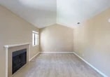 Located at 505 Pioneer Dr in Lodi, California, this three-bedroom, two-bathroom home offers a well-organized single-floor layout with notable architectural character. The living room serves as the heart of the home, showcasing striking vaulted ceilings that lend an open, airy feel to the space. A tiled fireplace with a classic surround anchors the room, complemented by plush carpeting and a ceiling fan. Natural light filters in through well-placed windows, adding warmth to the neutral, beige-toned walls throughout.

The kitchen features white cabinetry, a gas range, a full-size refrigerator, and a granite-style countertop that extends into a convenient breakfast bar—ideal for casual dining or additional prep space. A sink with a view into the adjoining living area keeps the layout connected and practical.

The bedrooms are carpeted and benefit from the same vaulted ceiling design, creating a sense of spaciousness. The primary bedroom includes a mirrored sliding-door closet that enhances the room's brightness. Additional bedrooms offer natural light through slatted blinds and window views of the surrounding greenery. The bathrooms feature granite-style countertops and framed mirrors. The exterior presents a stucco façade with a private balcony and landscaped surroundings.