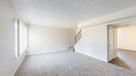 Located at 1170 Harwood Dr in Mansfield, Ohio, this two-story home offers a practical and well-organized layout spread across two floors. The main level features a living room with soft carpeting, neutral walls, and a textured ceiling, anchored by a staircase with a black metal railing that leads to the upper level. The transition from carpet to hardwood-style flooring near the entryway adds visual interest to the space. The kitchen is outfitted with white cabinetry, granite-style countertops, dark hardwood-style flooring, and stainless steel appliances including a refrigerator and electric range. A dishwasher and utility access are also present on this level. The full bathroom features a tub-shower combination, a white vanity, and dark hardwood-style flooring. Upstairs, three carpeted bedrooms provide comfortable living space, with the generously sized primary bedroom offering ample room for furnishings. The additional bedrooms each feature windows that bring in natural light and views of the surrounding greenery. Two closets, including a walk-in style closet with built-in shelving, offer practical storage. A hallway connects the upper-level rooms efficiently. The property also features a grassy outdoor area with mature trees visible from the upper-floor windows.