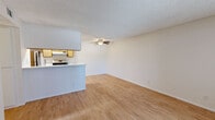 This 2-bedroom, 2-bathroom single-floor residence offers a functional and efficient layout with a clean, neutral aesthetic carried consistently throughout. The combined kitchen and living area forms the heart of the home, featuring warm wood-style flooring, a textured ceiling, and a ceiling fan that adds both comfort and visual interest. The kitchen is designed in a galley style with ample warm-toned wood cabinetry, a built-in gas range, a refrigerator, a dishwasher, and a peninsula counter that opens to the living area, creating a practical pass-through feel.

The living room is bright and open, benefiting from natural light and a straightforward flow toward the private areas of the residence. A hallway connects the main living space to the two bedrooms, a dedicated closet, and both bathrooms.

Both bedrooms are well-proportioned with the same warm wood-style flooring and textured ceilings. Each features a window fitted with vertical blinds, allowing natural light and outdoor views while maintaining privacy. The primary bedroom offers a comfortable footprint suited for a full bedroom setup.

The two bathrooms are cleanly finished, each with light wood vanities, white countertops, and matching flooring. One features a tub-shower combination with a curved curtain rod, while the other offers a compact, efficient layout. The overall ambiance is bright, clean, and move-in ready.