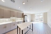 Located at 21 Charles Street in Cambridge, MA, this 2-bedroom, 2-bathroom residence offers a thoughtfully designed single-floor layout with modern finishes throughout. The open-concept kitchen and living area serves as the heart of the home, featuring light wood-look flooring, recessed lighting, and large sliding glass doors that lead to a balcony, filling the space with abundant natural light. The kitchen is well-equipped with taupe cabinetry accented by brushed gold hardware, a mosaic tile backsplash, stainless steel appliances including a French door refrigerator and dishwasher, a gas range, and a center island ideal for dining or prep work. The living area flows seamlessly from the kitchen, offering an airy, open feel with outdoor views. Both bedrooms feature wood-look flooring, neutral tones, and windows that bring in natural light and city views. The two bathrooms are finished with floor-to-ceiling white vertical tile, brushed gold fixtures, a glass-enclosed shower in one, and a soaking tub-shower combination in the other, complemented by white vanities with gold hardware. Additional conveniences include three closets, a dedicated laundry area, an entrance foyer, and a hallway connecting all rooms efficiently.