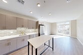 Located at 21 Charles Street in Cambridge, MA, this 2-bedroom, 2-bathroom residence offers a thoughtfully designed single-floor layout with modern finishes throughout. The open-concept kitchen and living area serves as the heart of the home, featuring light wood-look flooring, recessed lighting, and large sliding glass doors that lead to a balcony, filling the space with abundant natural light. The kitchen is well-equipped with taupe cabinetry accented by brushed gold hardware, a mosaic tile backsplash, stainless steel appliances including a French door refrigerator and dishwasher, a gas range, and a center island ideal for dining or prep work. The living area flows seamlessly from the kitchen, offering an airy, open feel with outdoor views. Both bedrooms feature wood-look flooring, neutral tones, and windows that bring in natural light and city views. The two bathrooms are finished with floor-to-ceiling white vertical tile, brushed gold fixtures, a glass-enclosed shower in one, and a soaking tub-shower combination in the other, complemented by white vanities with gold hardware. Additional conveniences include three closets, a dedicated laundry area, an entrance foyer, and a hallway connecting all rooms efficiently.