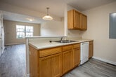 Located at 1175 Willow Run Dr in Abingdon, Virginia, this two-story home offers a clean, functional layout spread across two well-defined levels. The main floor features a welcoming living area with light-toned luxury vinyl plank flooring that runs throughout, complemented by neutral warm beige walls and textured ceilings. A large front-facing window allows natural light to fill the space, offering views of the surrounding neighborhood. The kitchen is accessible via a pass-through opening from the living area, showcasing warm honey-toned wood cabinetry, white countertops, a double sink, and an adjacent utility area with laundry hookups and additional storage space. Carpeted stairs lead to the upper level, where the bedrooms are situated. Each bedroom features plush carpet flooring, neutral walls, and a sliding-door closet with a built-in shelf and hanging rod. One bedroom includes a window overlooking the outdoor green surroundings. The bathrooms are finished with warm-toned vinyl flooring, wood vanity cabinetry, and a full tub-shower combination with clean white surrounds. Overall, the home presents a practical and comfortable living environment with consistent, neutral finishes throughout both floors.
