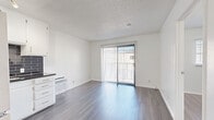 Located at 151 N Normandie in Los Angeles, this efficiently designed one-bedroom, one-bathroom unit offers a clean, modern aesthetic throughout. The combined kitchen and living area anchors the space, featuring sleek hardwood-style flooring and a textured ceiling. The kitchen stands out with white cabinetry, dark subway tile backsplash, black countertops, and stainless steel appliances including a full-size refrigerator and gas range. Track lighting overhead adds a contemporary touch, while a wall-mounted AC unit provides climate control. The living area is bright and open, with sliding glass doors fitted with vertical blinds that invite natural light and provide access to an outdoor area. The bedroom is a serene, light-filled room with large windows dressed in horizontal blinds, neutral walls, and matching hardwood-style flooring. A dedicated closet provides convenient storage. The bathroom is finished in a clean, all-white palette, featuring a shower-tub combo, tile flooring, and a vanity. Throughout the unit, the consistent use of neutral tones and modern finishes creates a cohesive and functional living environment well-suited to urban Los Angeles living.