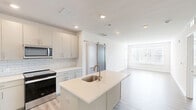 Located at 3000 Forge Circle in Lawrence Township, NJ, this well-appointed 2-bedroom, 2-bathroom residence offers a thoughtfully designed single-floor layout with a clean, modern aesthetic throughout. Light wood-style plank flooring flows seamlessly across the living areas and bedrooms, creating a bright and cohesive feel.

The contemporary kitchen serves as a central hub, featuring a large island with an undermount sink, crisp white quartz countertops, subway tile backsplash, soft-close cabinetry, and a full suite of stainless steel appliances including a refrigerator, range, microwave, and dishwasher. Recessed lighting illuminates the space effectively.

The spacious primary bedroom offers generous square footage, natural light from large windows with views of the surrounding greenery, and access to a private en-suite bathroom finished with wood-tone cabinetry, a glass-enclosed shower, tile flooring, and a white quartz vanity. A stylish barn door adds a modern design accent to the primary suite. The second bedroom is equally well-lit with its own window overlooking the outdoors. The second bathroom features a full soaking tub with tiled surround. Two closets and a hallway complete this efficiently organized, move-in-ready residence.