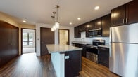 Located at 350 Maloney Dr in Fitchburg, Wisconsin, this single-floor unit offers a thoughtfully designed open-concept layout that seamlessly connects the kitchen and living areas. The kitchen is a standout feature, showcasing rich dark espresso cabinetry that extends to the ceiling for ample storage, granite countertops, and a full suite of stainless steel appliances including a refrigerator, electric range, built-in microwave, and dishwasher. A central island with a granite surface and pendant lighting above adds both functionality and visual appeal. Recessed lighting throughout the kitchen enhances the modern aesthetic.

The living area is generously proportioned, finished with warm hardwood-style flooring that carries throughout the main living spaces. Large windows invite an abundance of natural light and offer views of the surrounding neighborhood, while a door provides access to a private balcony. The bedroom is carpeted for comfort, featuring a large window that fills the room with daylight. The bathroom is clean and functional, complete with dark vanity cabinetry, granite countertops, tile flooring, and a full tub-shower combination. The overall design presents a contemporary and cohesive aesthetic throughout.
