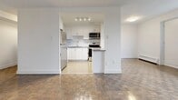 This well-appointed 3-bedroom, 1-bathroom unit in Mississauga, Ontario offers a thoughtfully designed layout across a single floor. The living room is generously sized, featuring warm parquet wood flooring in a classic herringbone pattern and crisp white walls that create a bright, open atmosphere. Large windows throughout the unit allow natural light to pour in while framing sweeping city skyline views, adding a sense of openness to the space.

The kitchen has been modernized with sleek white cabinetry, a white subway tile backsplash, stone countertops, and a full suite of stainless steel appliances including a refrigerator, dishwasher, stove, and microwave. Light tile flooring and recessed track lighting complete the clean, functional aesthetic. A breakfast bar connects the kitchen to the living area, enhancing the open-concept feel.

Each of the three bedrooms continues the parquet flooring theme and benefits from natural light via large windows with city views. The primary bedroom includes a mirrored sliding closet. Baseboard heating units are present throughout. The bathroom is finished with white subway tile walls extending from floor to ceiling around the tub-shower combo, complemented by a wood-toned vanity and light grey floor tiles, creating a clean and contemporary look.