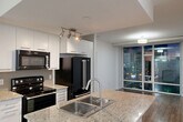Located in the heart of downtown Edmonton on Jasper Avenue, this two-bedroom, two-bathroom unit offers a well-designed single-floor layout that makes efficient use of its space. The open-concept living area seamlessly connects the kitchen, dining, and living zones, creating a cohesive and functional environment. The kitchen is a standout feature, equipped with white cabinetry, granite countertops, a double-basin stainless steel sink, black appliances including a French door refrigerator and electric range, and a central island that doubles as a prep and dining surface. Track lighting adds focused illumination throughout the kitchen area. Floor-to-ceiling windows in the living area flood the space with natural light and frame views of the Edmonton city skyline. Warm hardwood-style flooring runs consistently throughout the unit, complementing the clean white walls and textured ceilings. Both bathrooms are finished with granite-topped vanities, wood-style flooring, and full tub-shower combinations. The bedrooms are bright and functional, with the primary bedroom benefiting from large sliding glass doors that open to an outdoor balcony with urban views. A dedicated laundry area and closet complete the practical amenities of this well-appointed downtown residence.